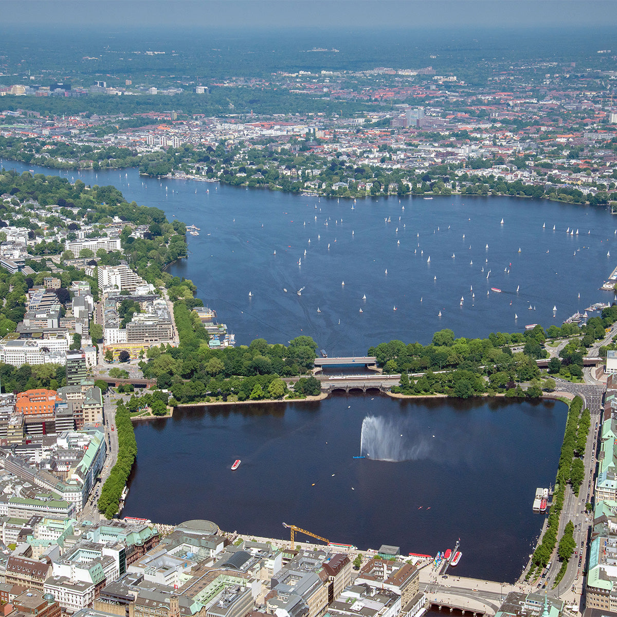 Aerial view of Hamburg’s Inner and Outer Alster lakes with numerous sailboats on the water and the city skyline surrounding the lakes.