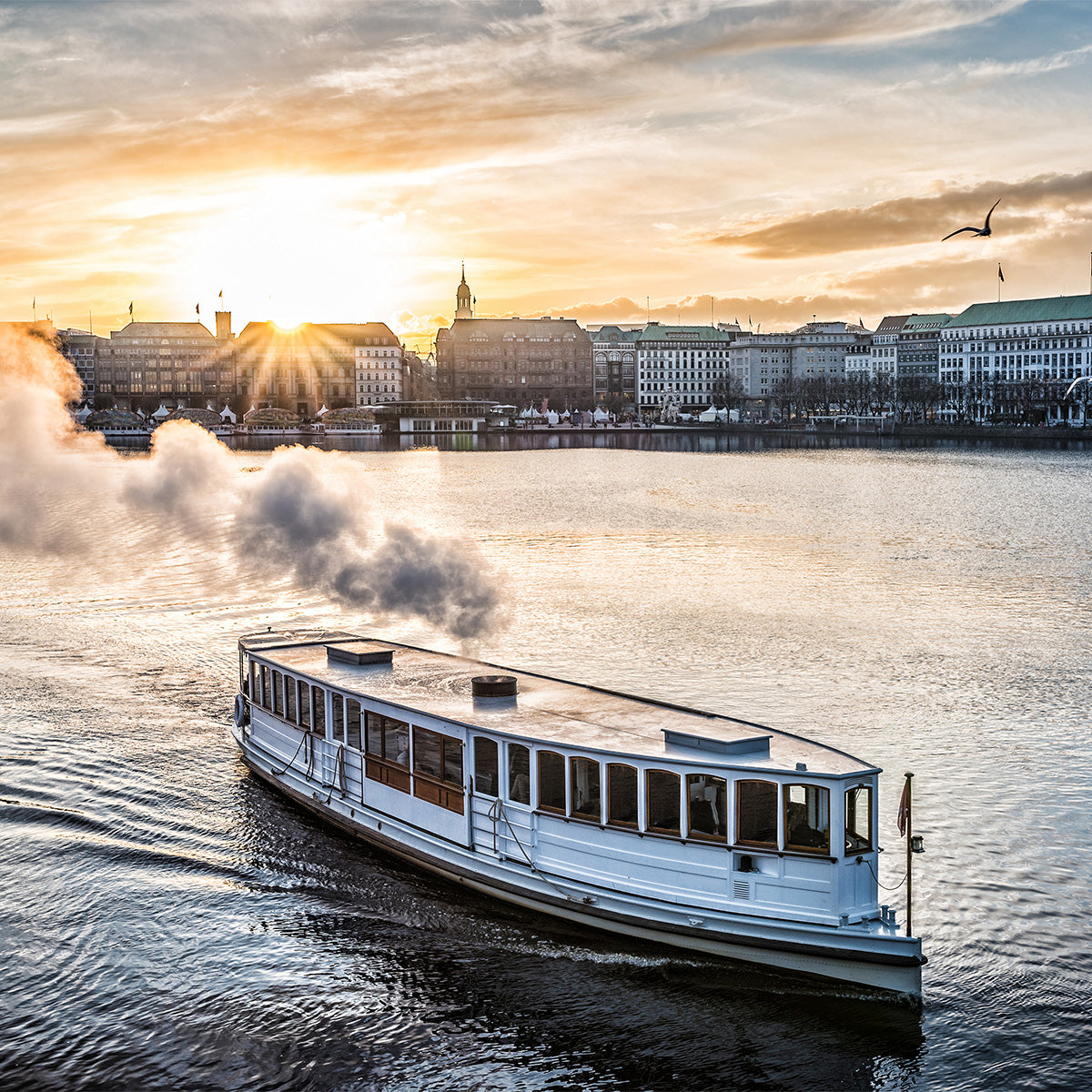 Historic white steam boat crossing Hamburg’s Inner Alster at sunrise, with city skyline in the background, golden sunlight over the water, and steam rising from the vessel